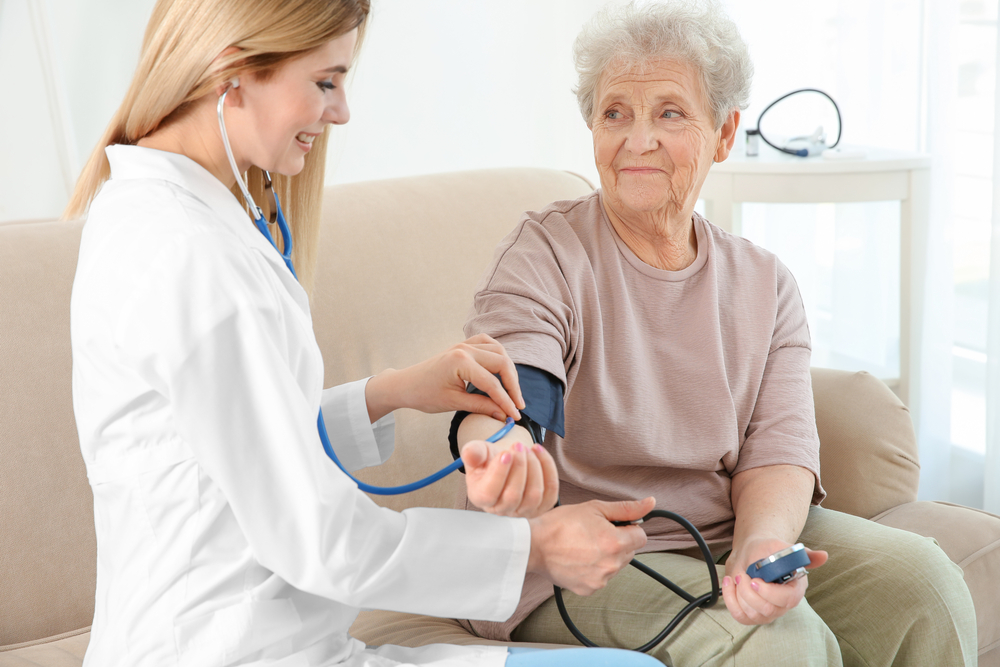 Young,Nurse,Measuring,Blood,Pressure,Of,Elderly,Woman,At,Home